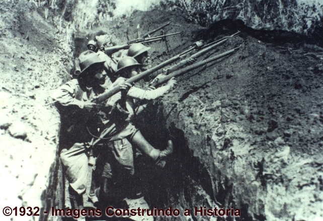 Trincheira constitucionalista no alto da serra no túnel. Notar a largura e profundidade da trincheira. O primeiro soldado está com o engenhoso dispositivo de lançamento de granadas de mão à distância, projetado e construído pelo Serviço de Engenharia da Escola Politécnica de São Paulo, chamado de “bocal-sabre lançador de granadas”. Esse mecanismo, simples e barato, causou uma verdadeira devastação nas tropas ditatoriais, que simplesmente não sabiam de onde vinha aquela “chuva” de granadas