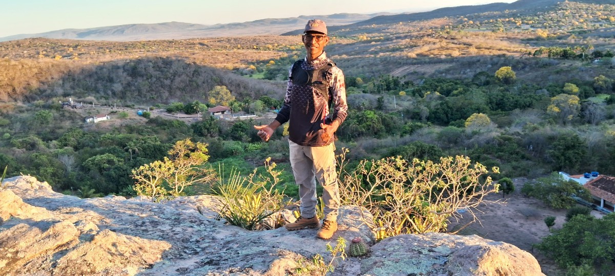 Ari Velon sobre forma&ccedil;&atilde;o rochosa com a paisagem de Tacaratu ao fundo