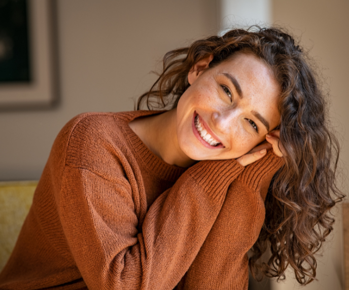 Foto de mulher com blusa marrom sorrindo