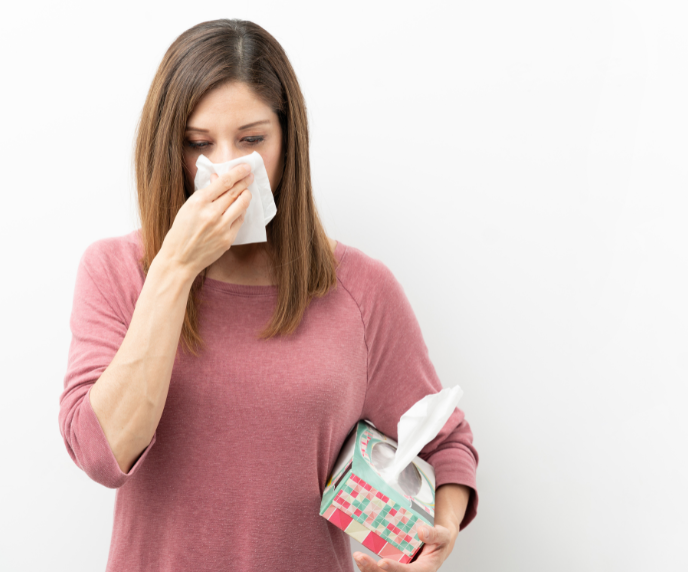 Foto de mulher assoando o nariz, gripe